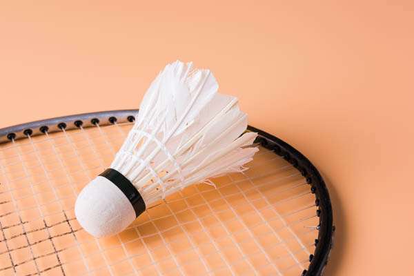 Shuttlecocks and badminton racket. Yellow background.